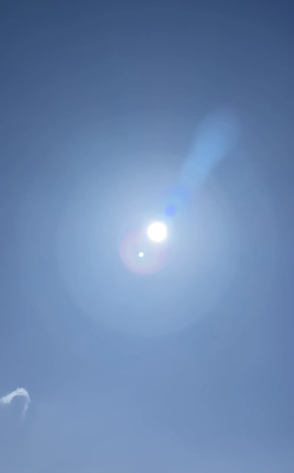 Real photograph of an open blue sky with the sun breaking through