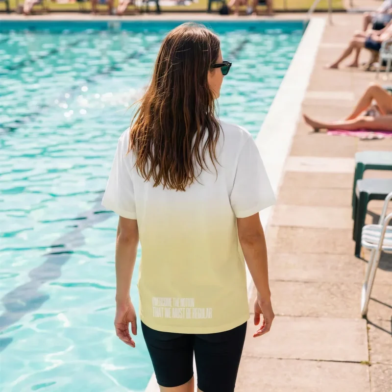 "Overcome the notion that we must be regular" Backprint Tee worn by a model